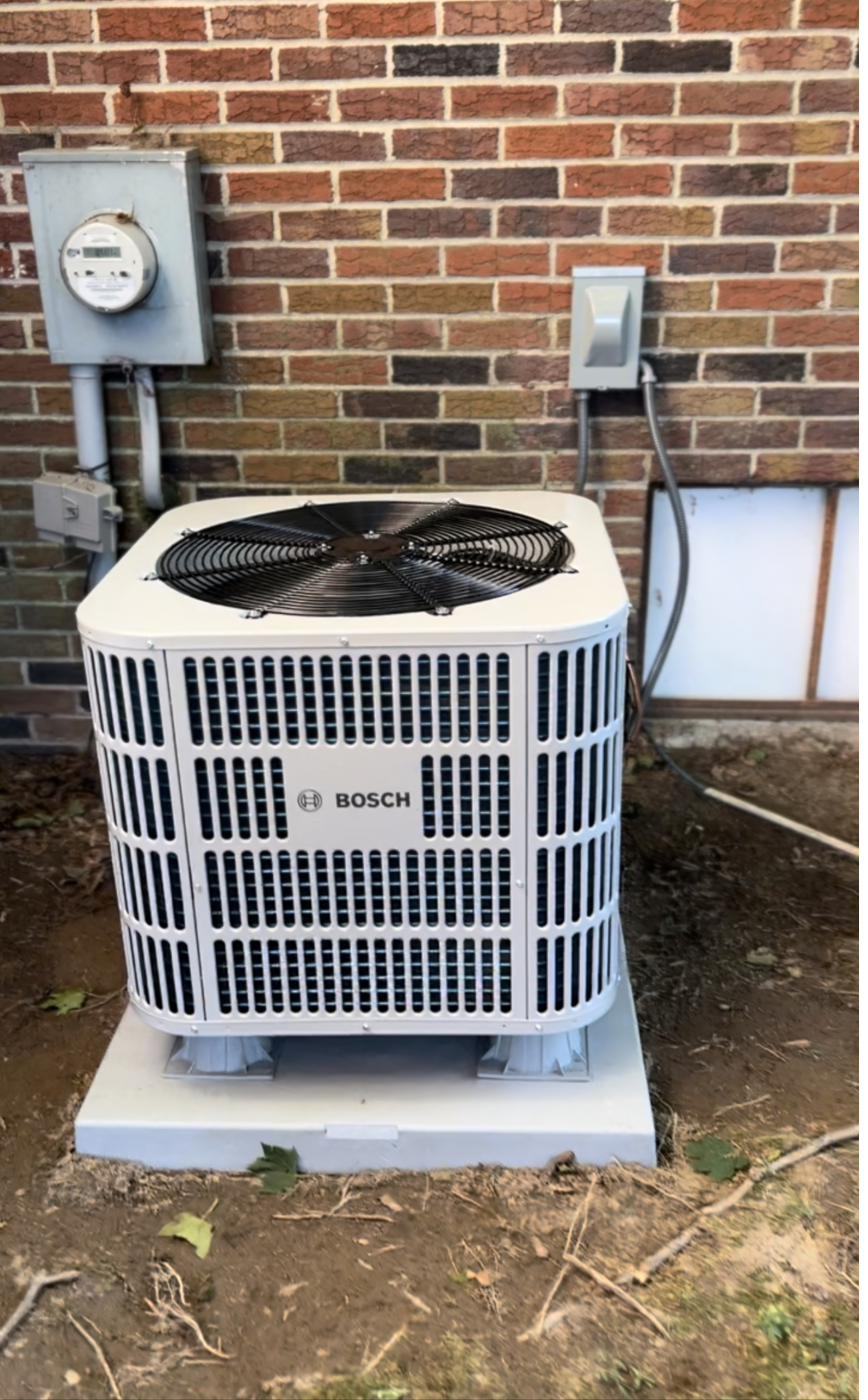 New outdoor air conditioning condenser installed beside a brick home