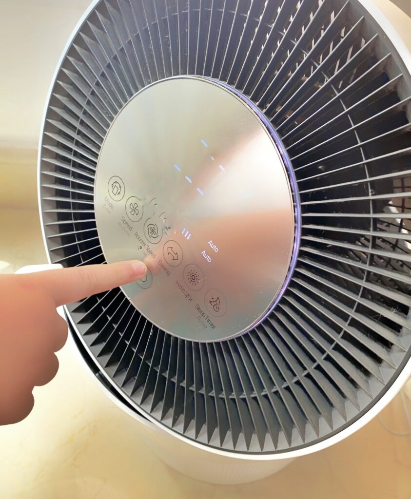 Child pushing button on room air purifier. Children using technology that improves quality of life