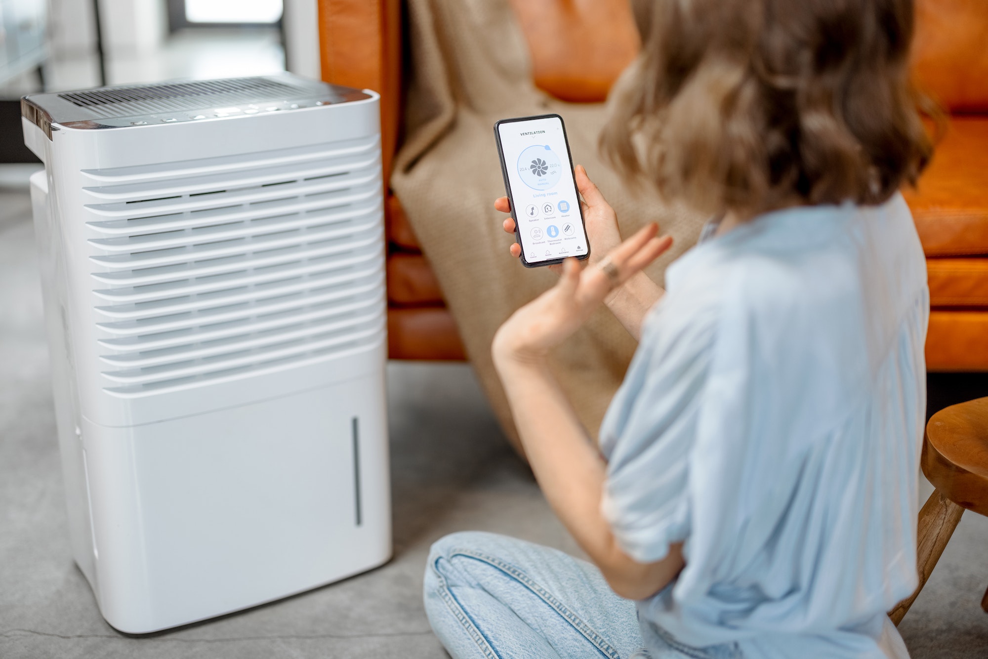 Woman sitting near air purifier and moisturizer appliance