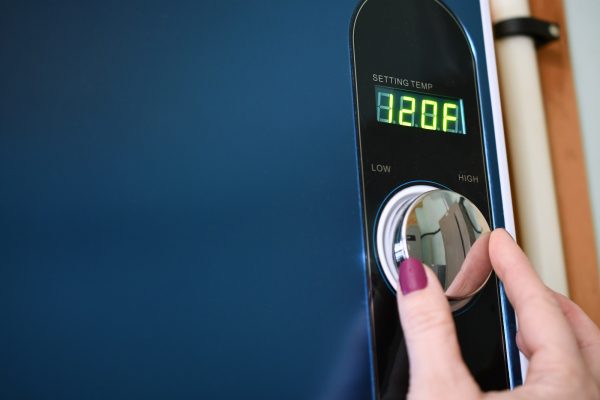 Female hand adjusting a tankless instant hot water heater. Energy efficient efficiency, conservation